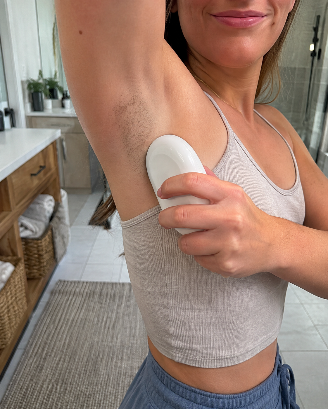 American woman doing an underarm grooming touch-up at home